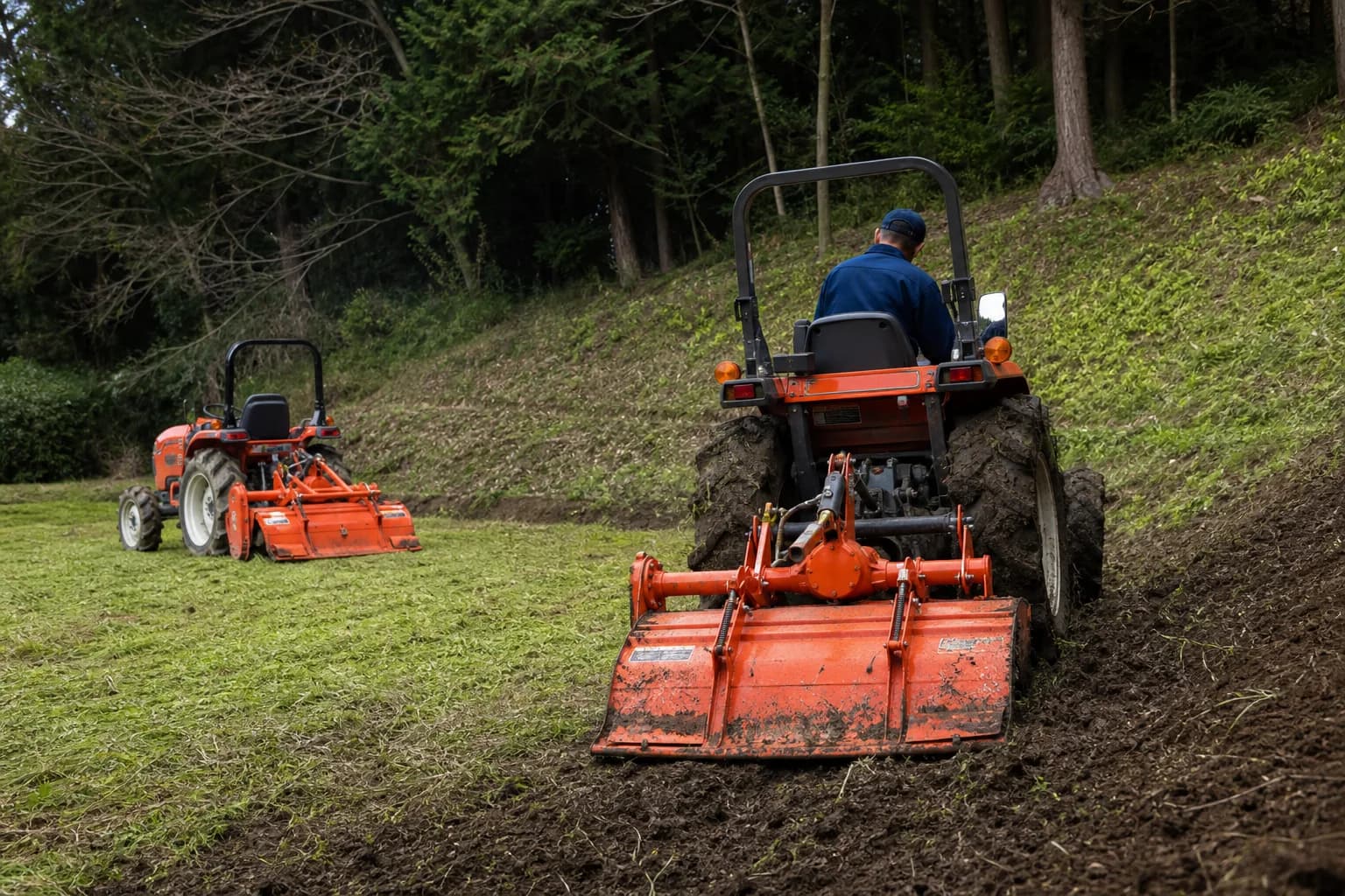 Dva kompaktné malotraktory pracujú na vidieckom pozemku, jeden na rovnej tráve a druhý v mäkšom teréne vo svahu.